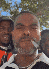 a man with a beard is smoking a cigarette in front of a group of men .