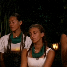 two women are sitting next to each other in front of a fire at night .