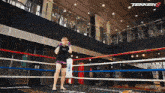 a woman in a boxing ring with a tekken 8 logo on the ceiling