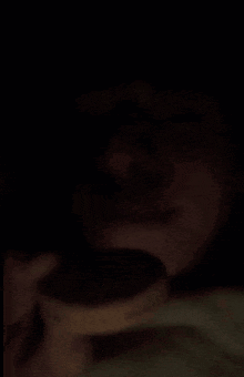 a close up of a person 's face in the dark with a cookie in the foreground
