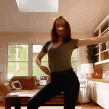 a woman in a green shirt is dancing in a living room