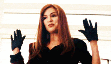 a woman is wearing black gloves and waving her hands