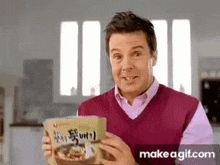 a man in a purple sweater is holding a bag of noodles .
