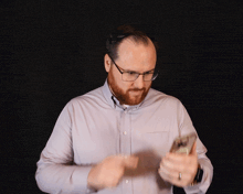 a man with glasses and a beard is looking at his cell phone