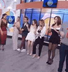 a group of women are dancing in a room with a man in a suit .