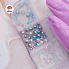 a purple glove holds a blue and white nail with a star on it