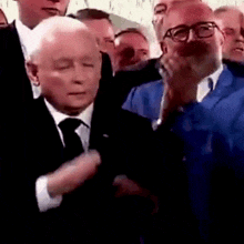 a man in a suit and tie is standing in a crowd of men .