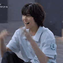a young man in a white shirt is laughing with his mouth open