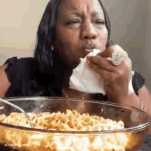 a woman is eating macaroni and cheese with a napkin in her mouth