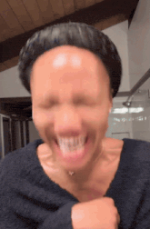 a woman in a black sweater is making a funny face with her eyes closed