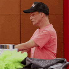 a man wearing a pink shirt and a black hat with the letters g on it