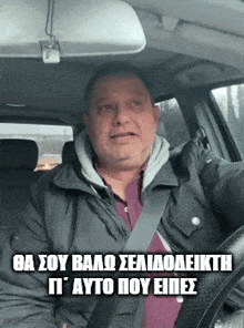a man is sitting in a car with a foreign language written on the bottom of the image