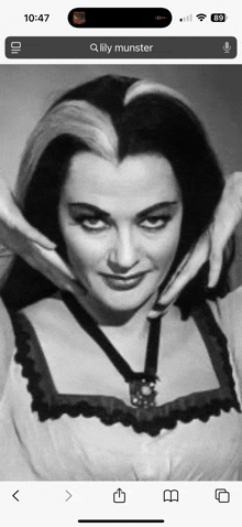 a black and white photo of lily munster on a cell phone