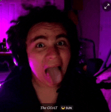 a man wearing headphones is sticking his tongue out in front of a purple background .