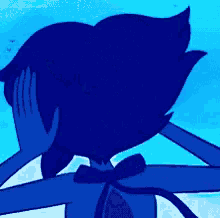 a person is touching a blue cartoon character 's face with a fork .