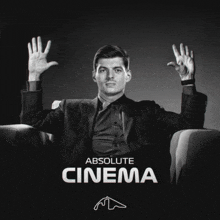 a man in a suit sits in a chair with his hands in the air and the words absolute cinema behind him