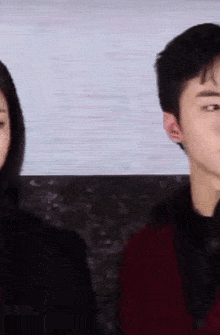 a man and a woman are standing next to each other and the man is wearing a red sweater