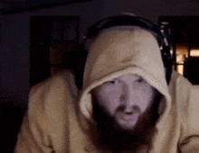 a man with a beard wearing headphones and a hooded sweatshirt
