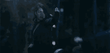 a woman in a black coat is standing in the rain holding a gun .