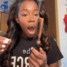 a woman wearing a black shirt that says " age " is holding a brush