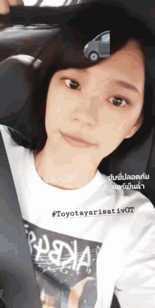 a girl wearing a toyota yarisativ gt shirt takes a selfie