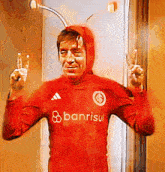 a man in a red banrisul shirt giving the peace sign