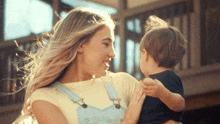 a woman in overalls holds a small child
