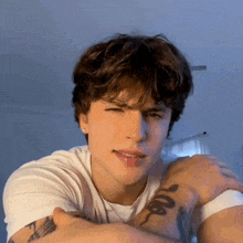a young man with a tattoo on his arm looks at the camera .