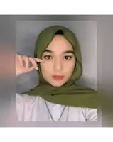 a woman wearing a green hijab and a white shirt looks at the camera