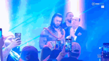 a group of people are taking pictures of a wrestler on a tv screen