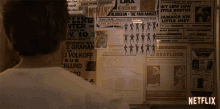 a man is looking at a wall full of wrestling posters including one for j volkoff jr.
