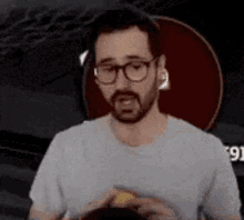 a man with a beard and glasses is holding a bottle of beer .