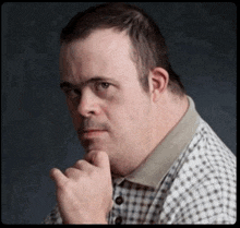 a man with down syndrome is wearing a plaid shirt