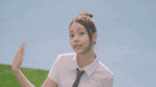 a girl in a white shirt and blue skirt is dancing on a grassy hill