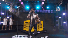 a man singing into a microphone in front of a yellow crate that says jimmy on it