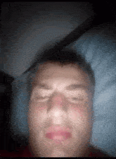 a man laying in bed with his eyes closed and his mouth open