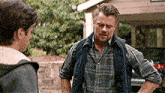 a man in a plaid shirt is talking to another man .