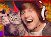 a man wearing headphones holds a cat in front of a colorful background