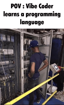 a man in a blue hat is standing in front of a electrical box with the words pov vibe coder learns a programming language