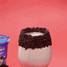 a cup of oreo cookies is next to a glass
