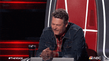 a man is sitting in a chair with a nbc logo on the bottom