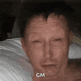 a man is laying in bed with his eyes closed and the word gm is on his face .