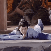 a young man in a kimono is laying on the ground with his feet crossed .