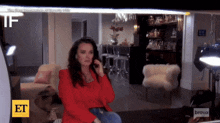 a woman in a red jacket is talking on a cell phone in front of a sign that says et