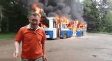 a man is standing in front of a burning bus