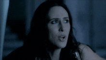 a woman with long dark hair is looking at the camera
