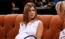 a pregnant woman is sitting on a couch talking to a woman .