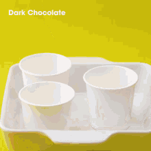 dark chocolate is being poured into three cups