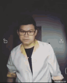 a man wearing glasses and a white jacket is made with scissors in the corner