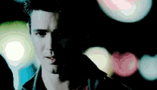 a close up of a man 's face with a blurry background of lights